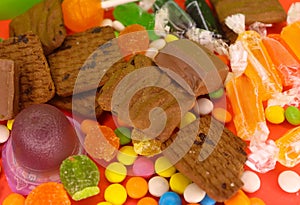 Mix colorful candies and chocolate with biscuits on the red background