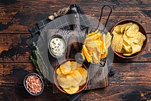 Mix of Crinkle Potato chips served with dip sauce and sea salt. Wooden background. Top view