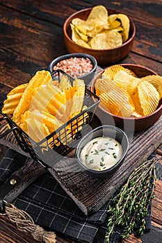 Mix of Crinkle Potato chips served with dip sauce and sea salt. Wooden background. Top view