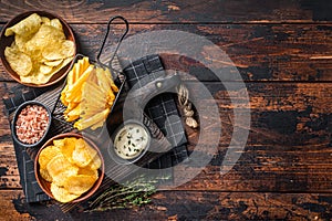 Mix of Crinkle Potato chips served with dip sauce and sea salt. Wooden background. Top view. Copy space