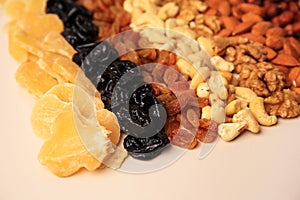 Mix of delicious dried nuts and fruits on beige background, closeup