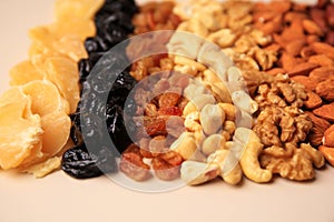 Mix of delicious dried nuts and fruits on beige background, closeup