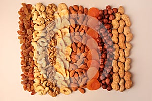 Mix of delicious dried nuts and fruits on beige background, flat lay