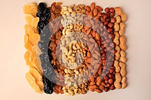Mix of delicious dried nuts and fruits on beige background, flat lay