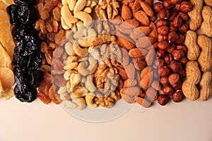 Mix of delicious dried nuts and fruits on beige background, flat lay