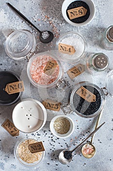 Mix of different salt types on grey concrete background. Sea salts, black and pink Himalayan salt crystals, powder. collection of