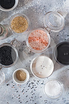 Mix of different salt types on grey concrete background. Sea salts, black and pink Himalayan salt crystals, powder. collection of