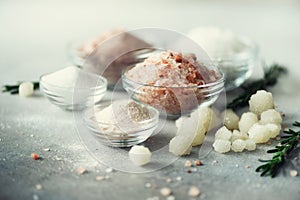 Mix of different salt types on grey concrete background. Sea salts, black and pink Himalayan salt crystals, powder photo