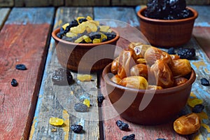 Mix of different varieties of dried fruits on wooden background - dates, apricots, prunes, raisins. Organic healthy food. Excellen