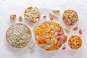 Mix of dried fruits, assorted nuts and seeds on a white table.