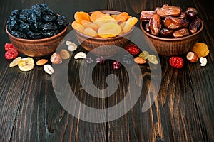 Mix of dried fruits and nuts on a dark wood background with copy space. Symbols of judaic holiday Tu Bishvat.