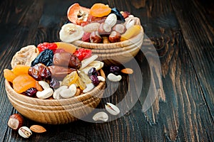 Mix of dried fruits and nuts on a dark wood background with copy space. Symbols of judaic holiday Tu Bishvat.