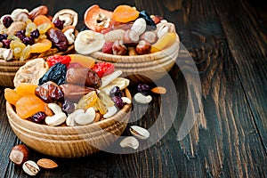 Mix of dried fruits and nuts on a dark wood background with copy space. Symbols of judaic holiday Tu Bishvat.
