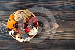Mix of dried fruits and nuts on a dark wood background with copy space. Top view. Symbols of judaic holiday Tu Bishvat.
