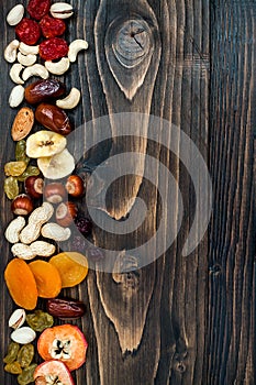 Mix of dried fruits and nuts on a dark wood background with copy space. Top view. Symbols of judaic holiday Tu Bishvat.