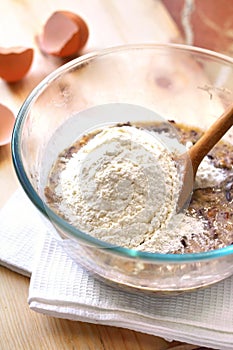 Mix of flour, eggs, bananas and chopped dark chocolate and walnuts in glass bowl