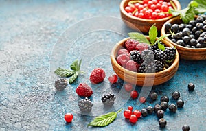 Mix of fresh berries with leaves on textured metal background