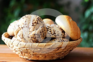 Mix fresh bread in basket on wooden background in still life.