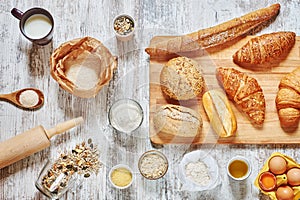 Mix of fresh bread and ingredients on a wooden table.