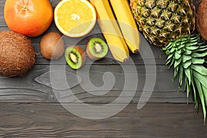 mix of fresh coconut, banana, kiwi fruit, orange and pineapple on dark wooden background. top view with copy space