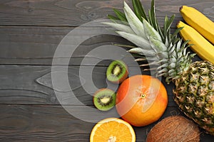 mix of fresh coconut, banana, kiwi fruit, orange and pineapple on dark wooden background. top view with copy space