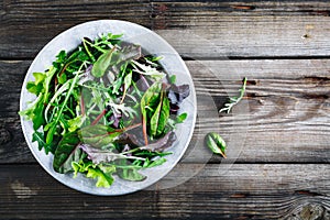 Mix of fresh leaves with arugula, lettuce, beets. Ingredients for salad on a wooden background