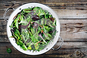 Mix of fresh leaves with arugula, lettuce, beets. Ingredients for salad on a wooden background