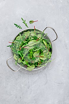 Mix of fresh leaves with arugula, lettuce, spinach, beets. Ingredients for salad on a gray stone background