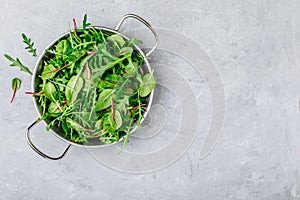 Mix of fresh leaves with arugula, lettuce, spinach, beets. Ingredients for salad on a gray stone background