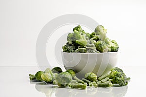 A mix of frozen green vegetables: beans peas broccoli Brussels sprouts in bowl on white background