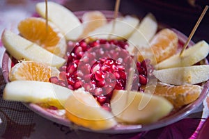 Mix fruit in plate, red pomegranate berries, orange, apple