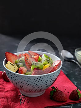 Mix fruit salad with yogurt on black background