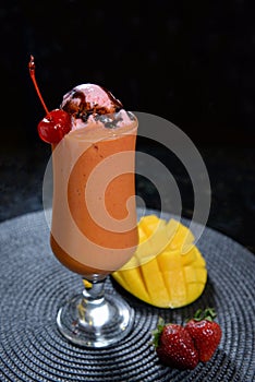 mix fruit shake of mango, strawberry, cherry and ice cream served in a glass isolated on dark background side view