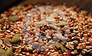 Mix of green sunflower seeds and black and brown sesame seeds with unfocused foreground and background.