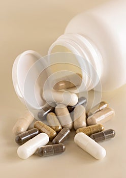 Mix of medical capsules in a bottle on light beige close up. Taking dietary supplements