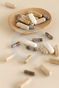 Mix of medical capsules in a bowl on light beige close up. Taking dietary supplements