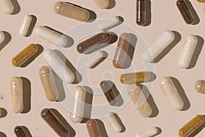 Mix of medical capsules on light beige top view, hard shadows. Taking dietary supplements