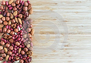 Mix of nuts: pistachio, almond, hazelnut, peanut, walnut fill the left part of the image, the right part is empty