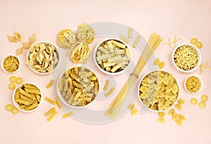 Mix of pasta shapes varieties on pink background