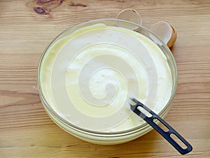 Mix pounded chicken egg yolks with sugar and beaten egg whites in a glass bowl on a wooden background.