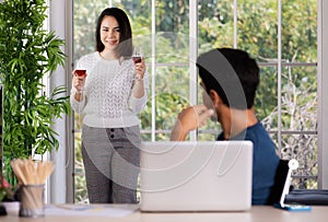 Mix race family lovers, Caucasian husband and Asian wife, man working at desk with laptop computer and woman taking couple of red