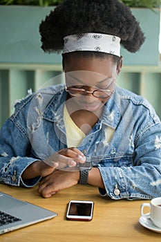 Mix-raced business woman looking at smart watch, working at office with tablet.