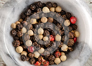 Mix of Red, White, and Black Peppercorns In Marble Bowl