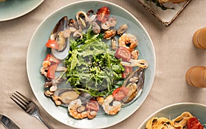 Mix salad with seafood shrimp, squid and arugula on a light background. Top view.