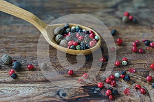 mix of spice peppers in a wooden spoon on a wooden background in rustic style