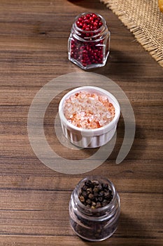 Mix of spices, grains of red and black pepper, pink himalayan salt and wooden box with cherry tomatoes