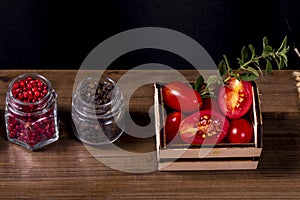 Mix of spices, grains of red and black pepper, pink himalayan salt and wooden box with cherry tomatoes