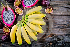 Mix of tropical fruits with banana, passion fruit and dragon fruit on a wooden background.