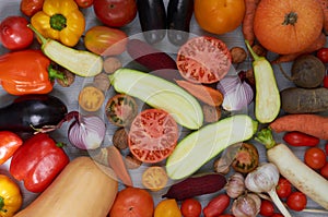 Mix of various fresh organic vegetables: carrots, garlic, eggplants, zucchini, beet, tomatoes on the gray background