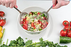 Mix vegetable salad with spoons in a bowl.